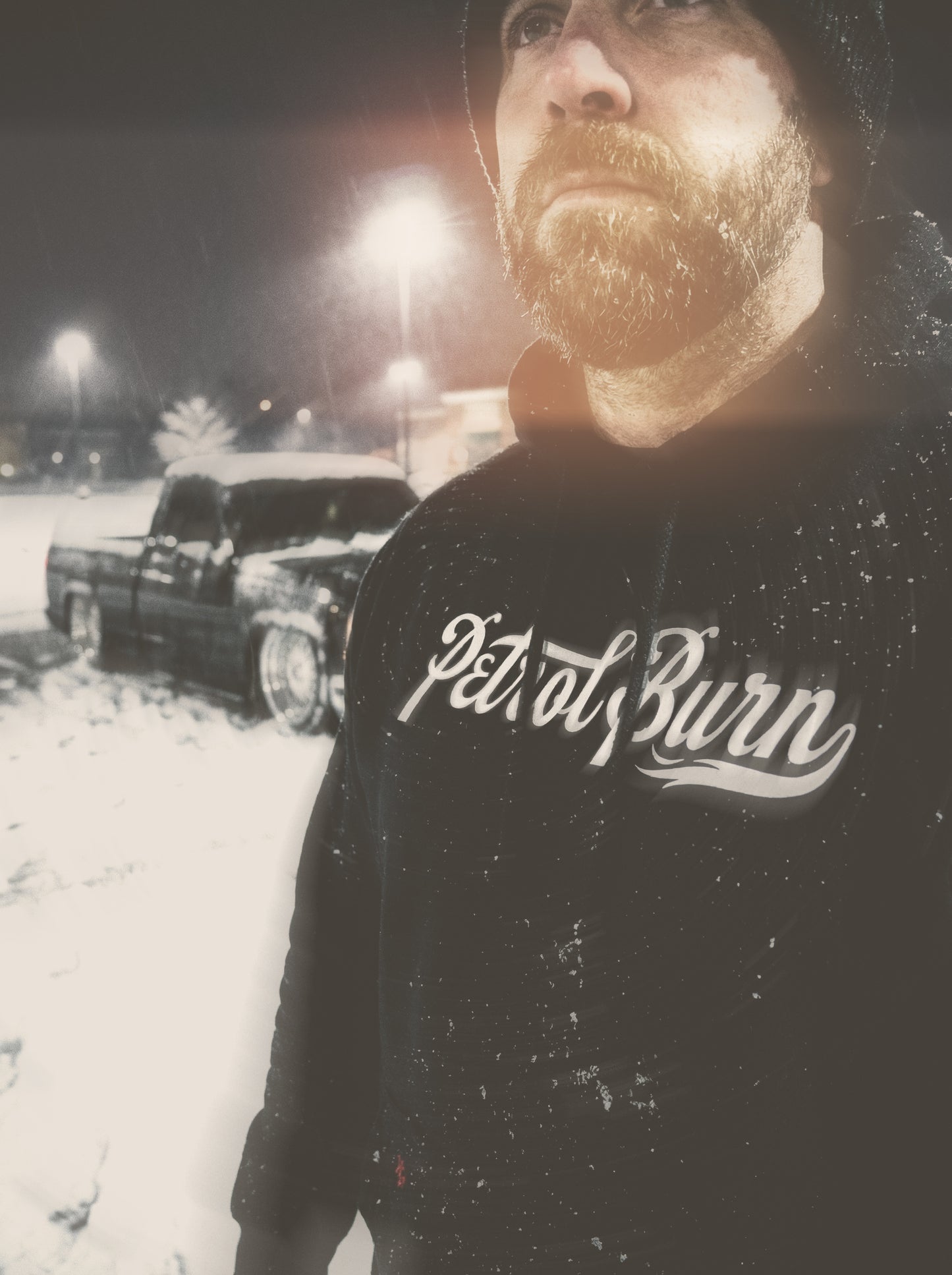 Person wearing a hoodie with 'Petrol Burn' text in a snowy outdoor setting